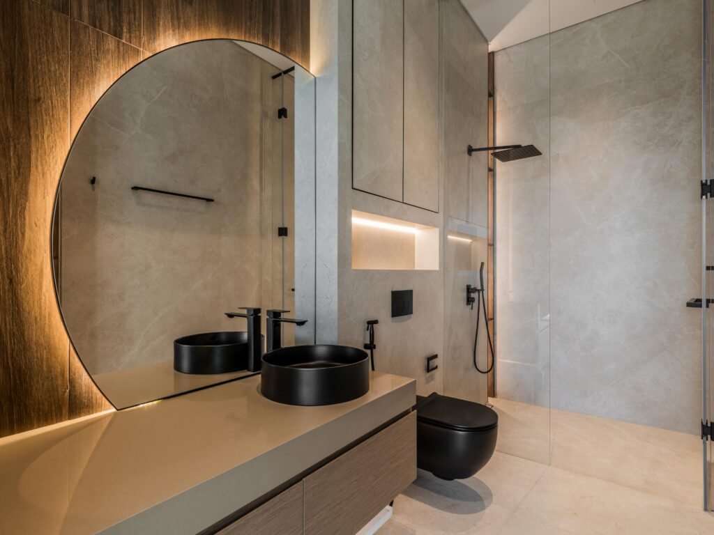 Bathroom in grey stone with arched backlit mirror and black vessel basins, Harrisoni Villas, La Mer South, Jumeirah 1, Dubai