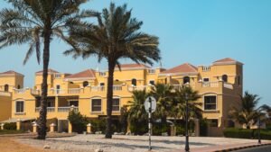 Low rise sand coloured villas with terracotta roofs and date palms in a Dubai villa community